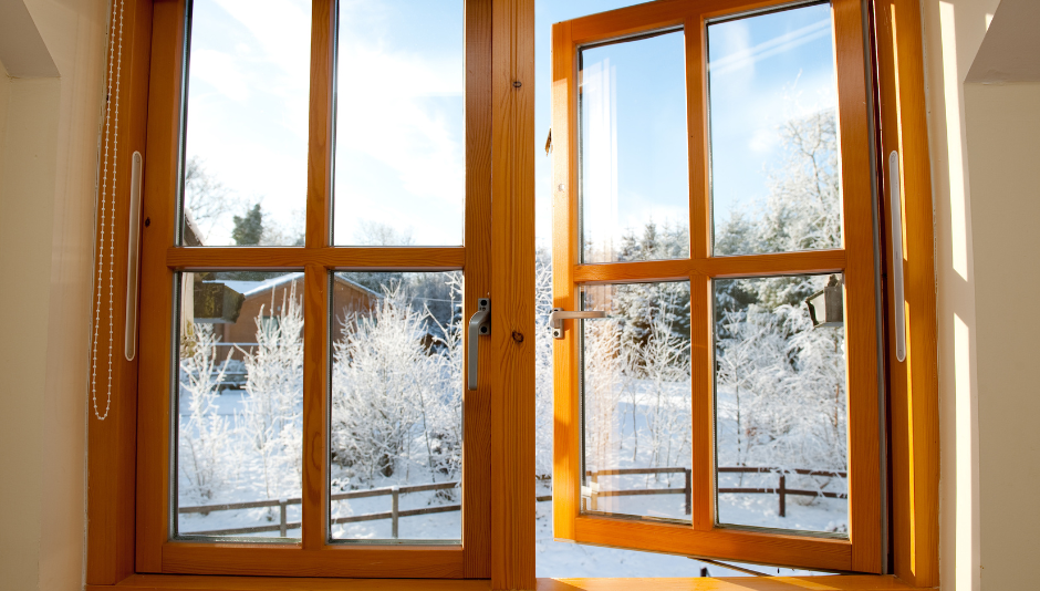 Finestra in legno che si affaccia su un paesaggio innevato